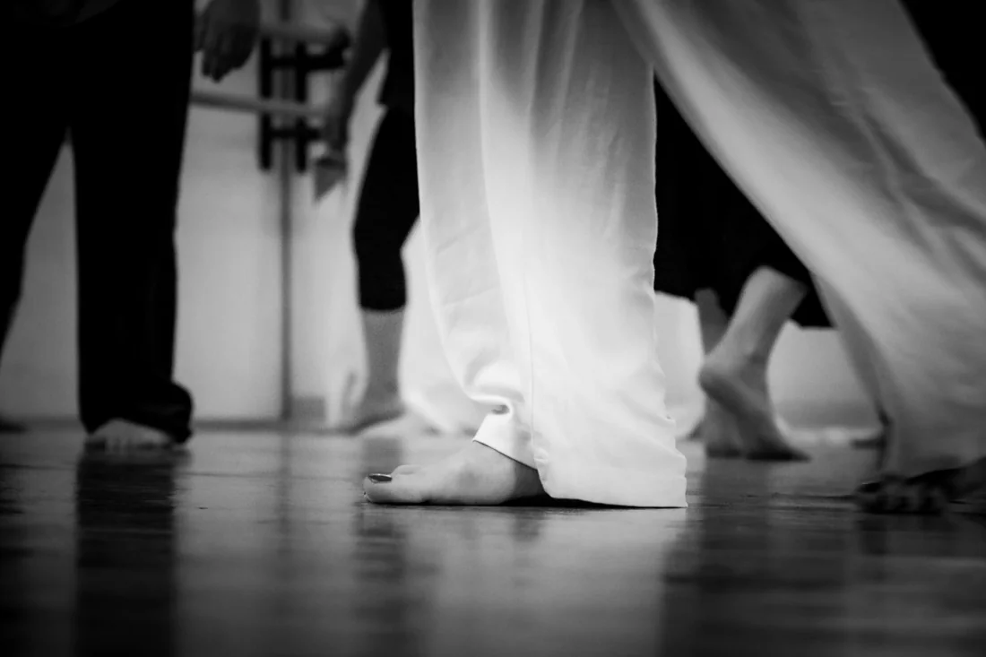 Pieds nus de danseurs sur le parquet d'une salle de danse-thérapie, ancrage et présence