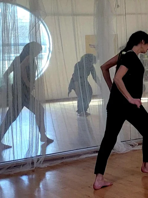 Participante en mouvement à travers des voiles lors d'une formation en danse-thérapie